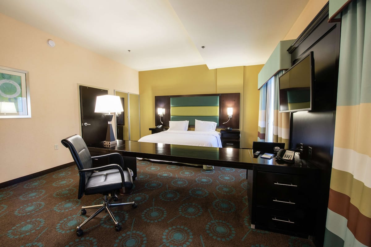 A hotel room with a bed, desk, chair, and a television.