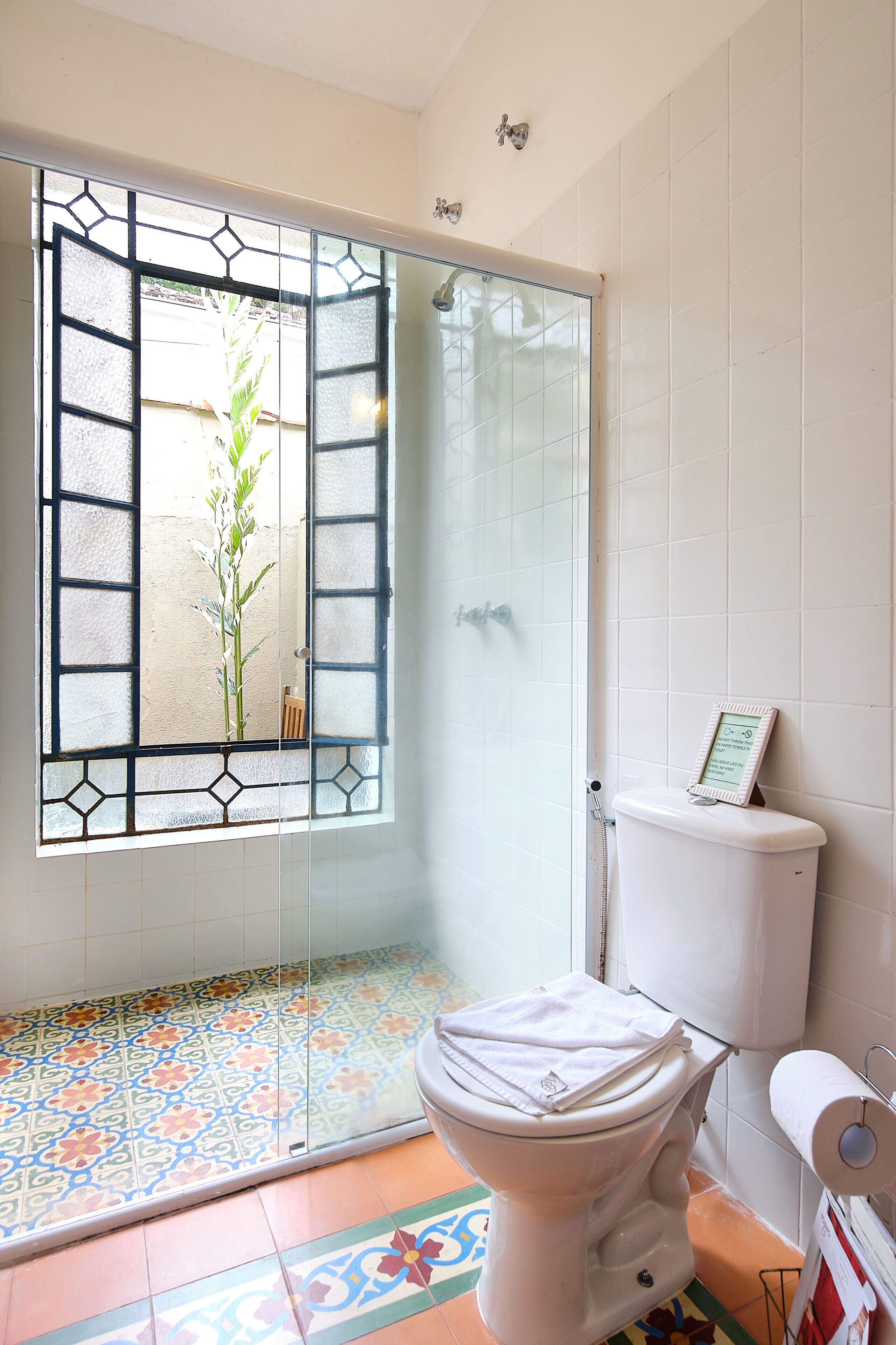 A bathroom with a glass door shower, a toilet, and a patterned floor.