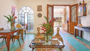 A dining area with a wooden table, chairs, and a glass-top coffee table with books and a vase. - Pousada Pontal Gardens (Paraty)