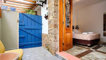 A room with a bed, a wooden door, a blue gate, and a stone wall.