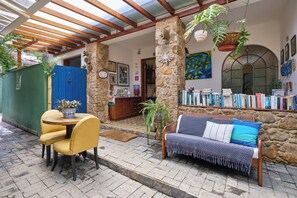 A cozy patio with a wooden bench, yellow chairs, and a table with a potted plant. - Pousada Pontal Gardens (Paraty)