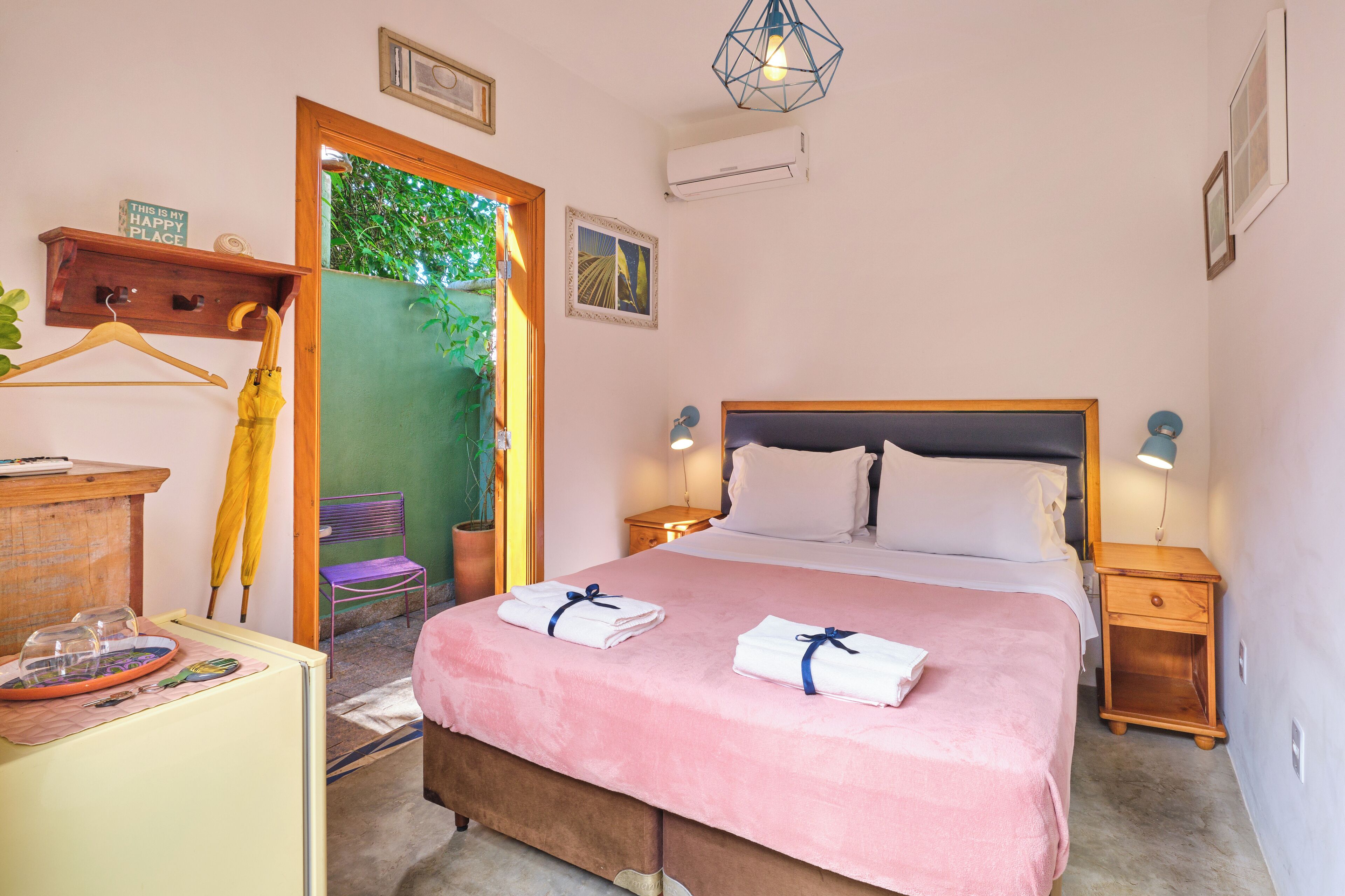 Un dormitorio ordenado con cama, mesitas de noche, cómoda y una silla.
