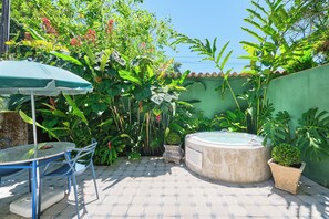 An outdoor patio with a table and chairs, a hot tub, and lush tropical plants. - Pousada Pontal Gardens (Paraty)