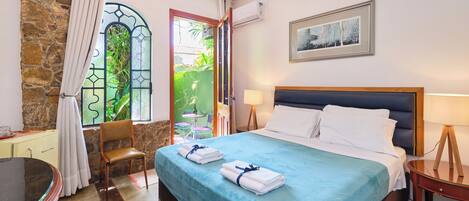 Una habitación de hotel con cama, una silla, escritorio, mesa y ventana con cortinas.