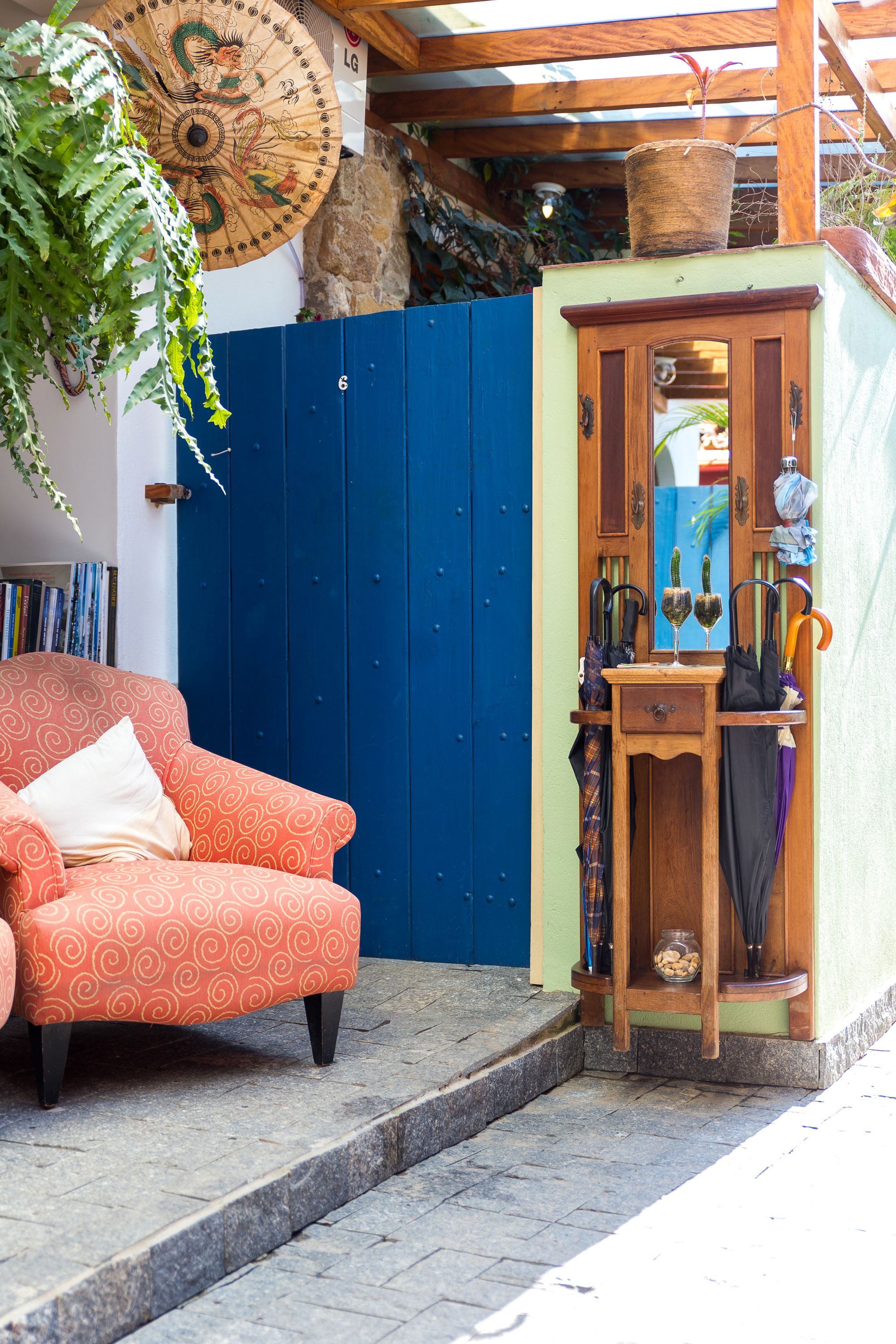 Un área de estar al aire libre acogedora, con una silla naranja estampada, una pequeña mesa de madera con sombrillas, y una sombrilla decorativa con diseño de dragón.