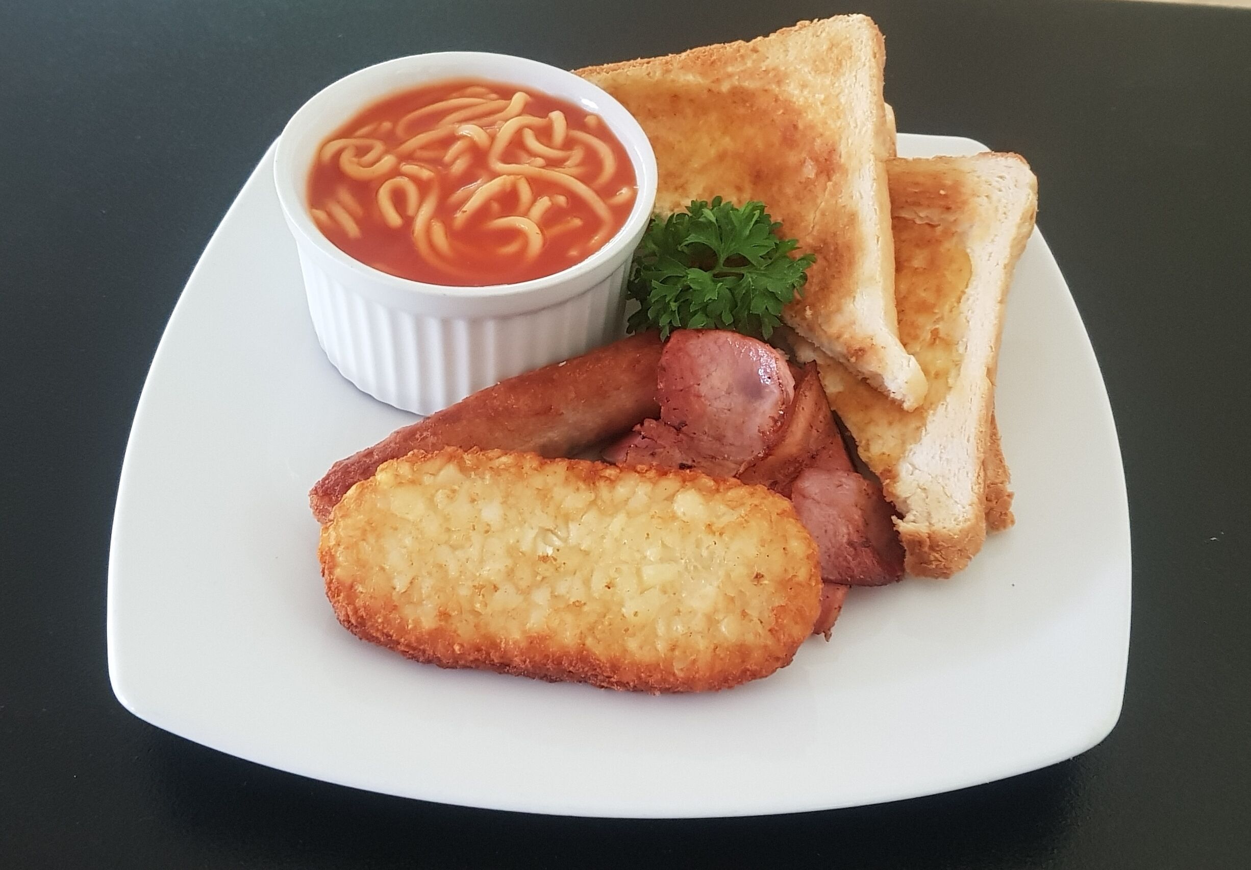 A plate with toast, sausage, and a bowl of soup.