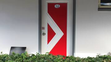 A door with a red and white arrow design, a number 12 sign, and a small no-smoking sign.