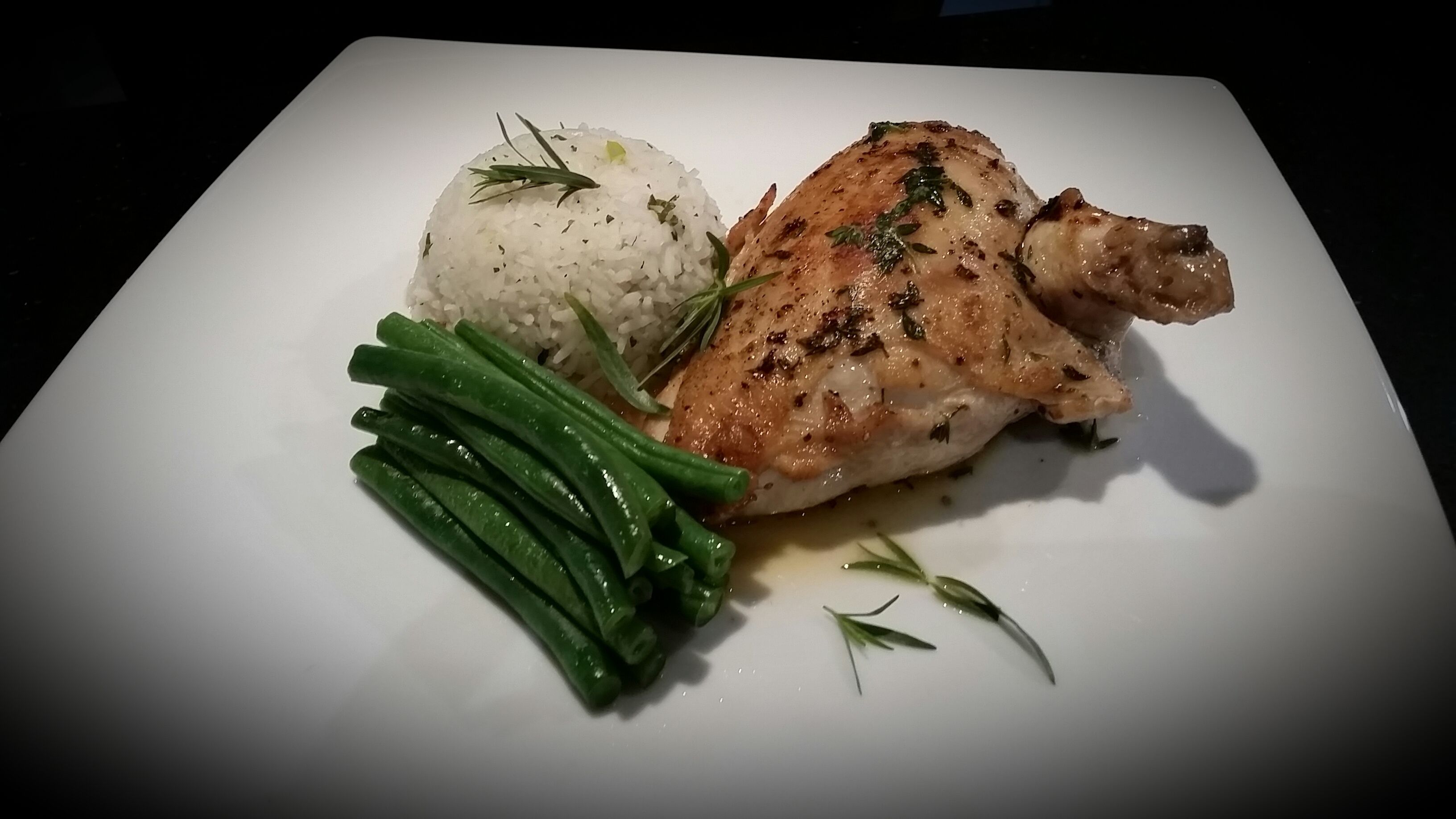 A white plate with a grilled chicken leg, a mound of white rice, and green beans.