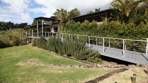 A modern building with a covered walkway, surrounded by lush greenery and palm trees. - Red Bridge Motor Inn (Woombye)