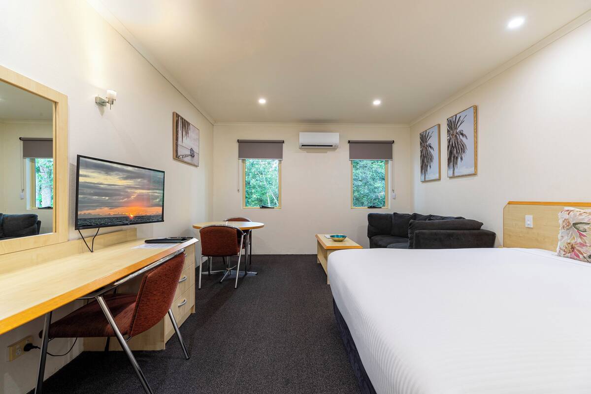 A hotel room with a bed, desk, chair, and a TV.