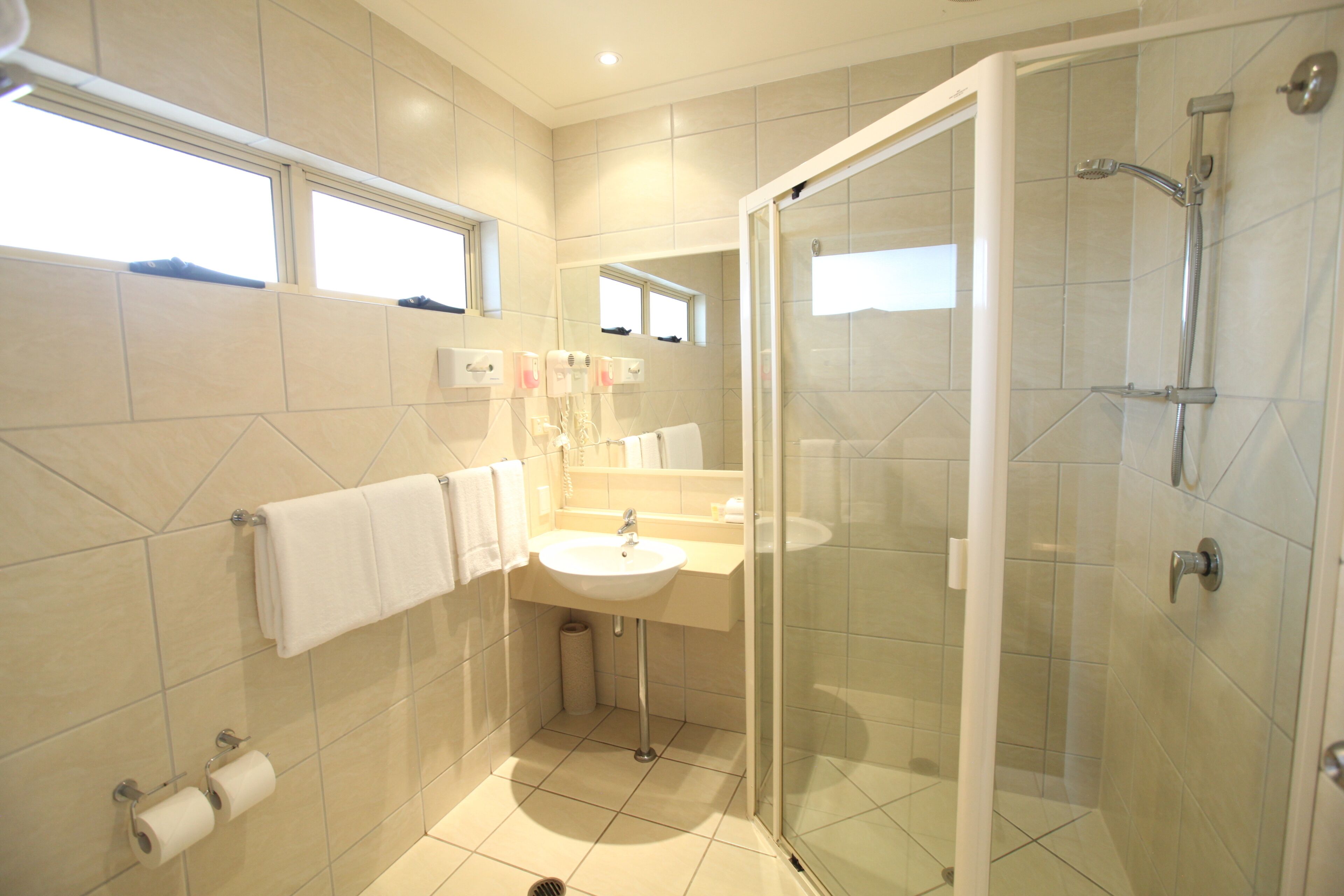 Une salle de bain moderne avec une douche à parois de verre, un lavabo et un miroir.