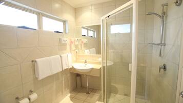 Une salle de bain moderne avec une douche à parois de verre, un lavabo et un miroir.