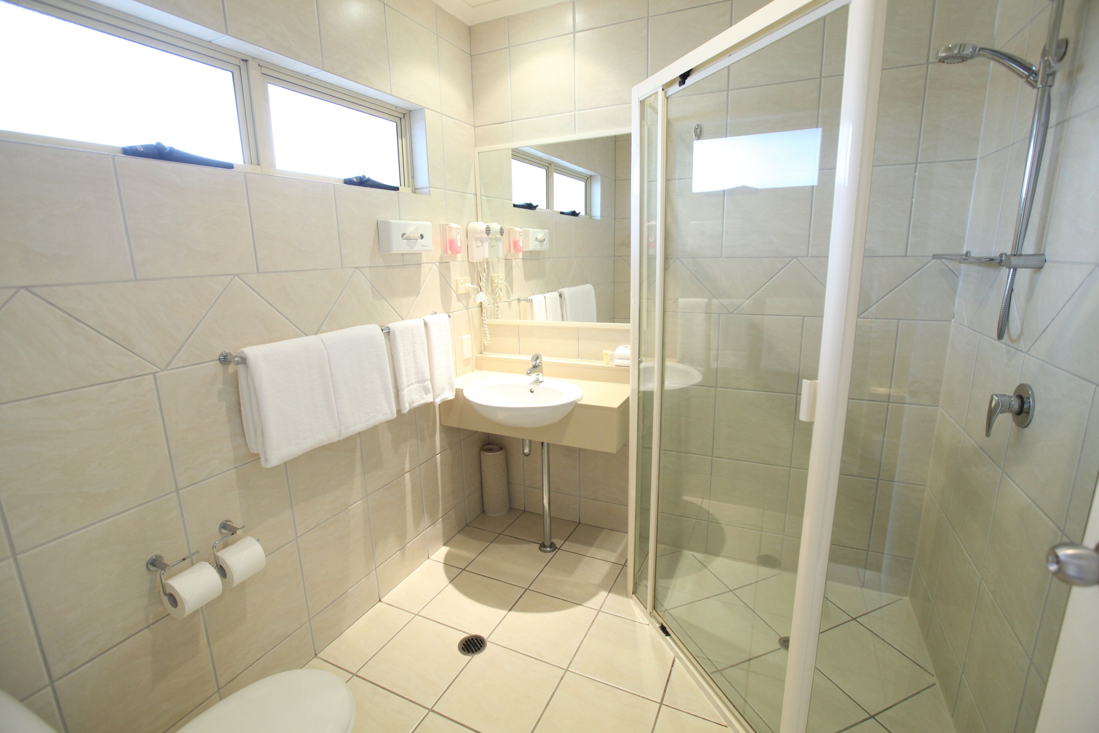 Un bagno moderno con doccia vetrata, lavandino e water.