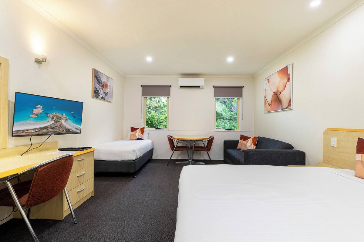 A hotel room with a bed, a desk, a chair, a small table, and two sofas.