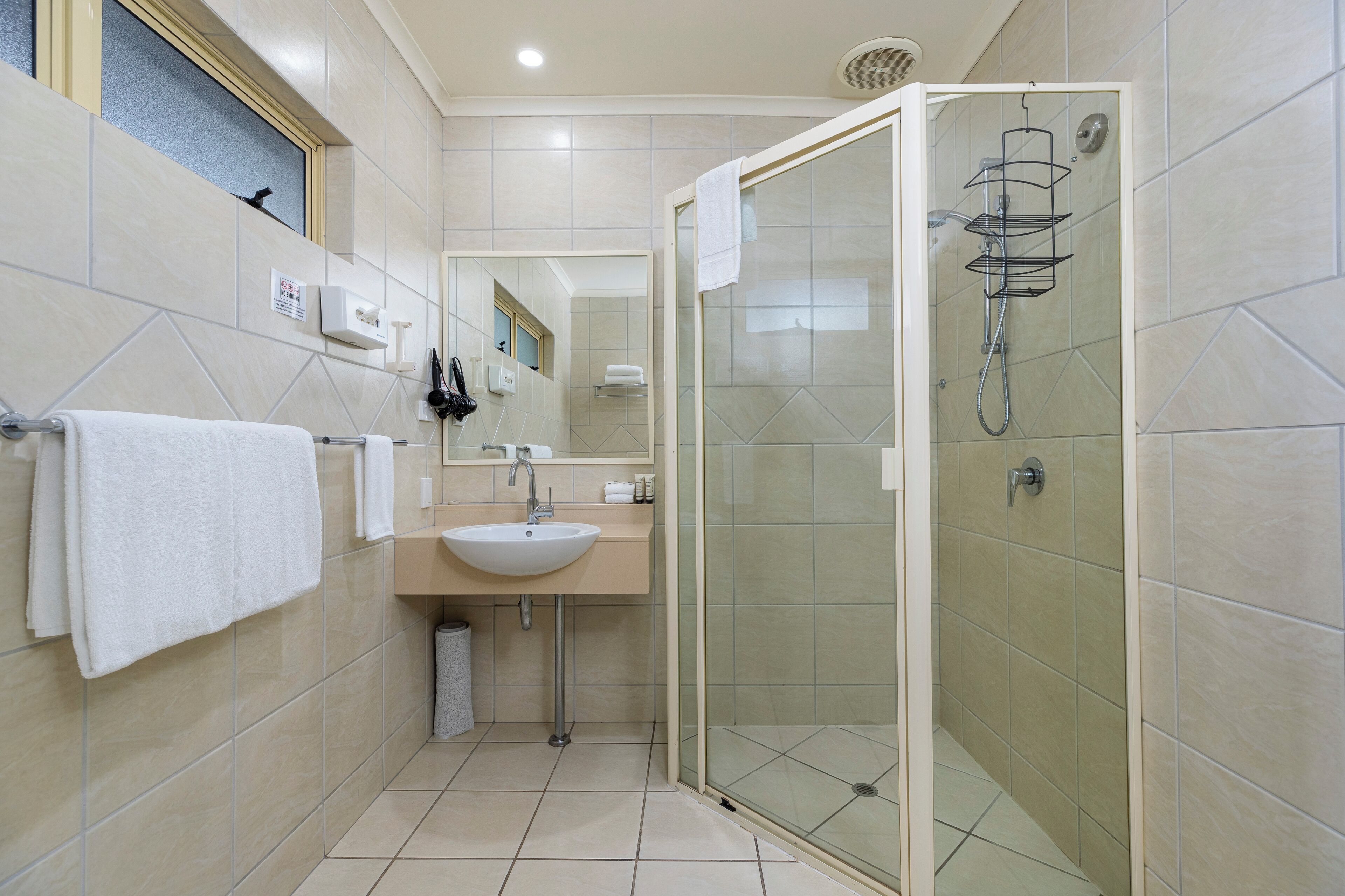 A modern bathroom with a glass-enclosed shower, a sink with a mirror, and a towel rack.