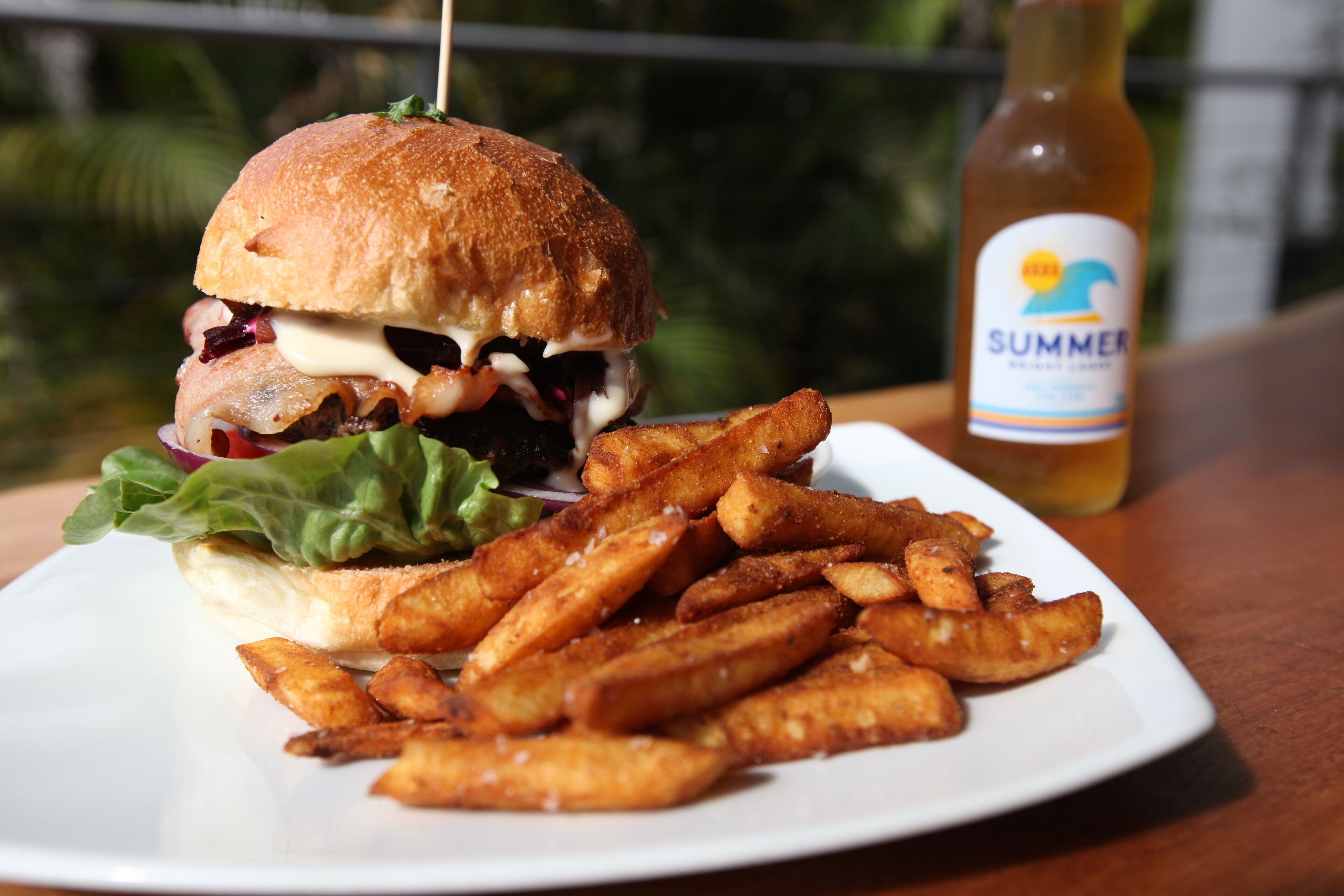 Un plato con una hamburguesa y papas fritas, y una botella de bebida Summer.
