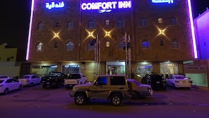Edifício Comfort Inn com letreiros iluminados e um estacionamento com vários carros.