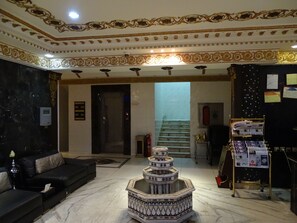 A lobby with a black leather sofa, a decorative tiled fountain, and a reception desk with a bulletin board. - Comfort Inn Al Yarmouk (Riyadh)