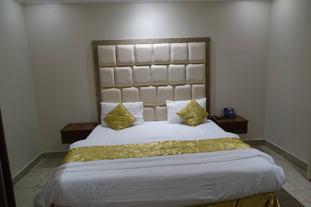 Una camera d'albergo con un letto grande, due comodini e una testiera imbottita.