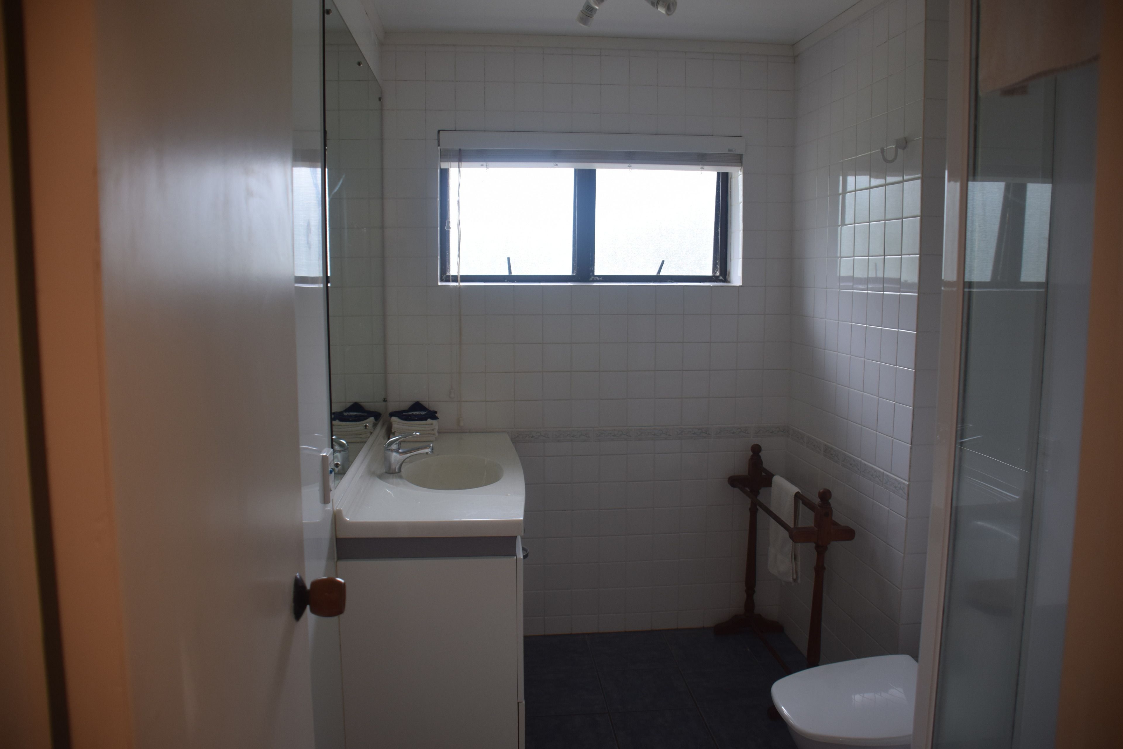 A small, clean bathroom with a sink, mirror, and toilet.