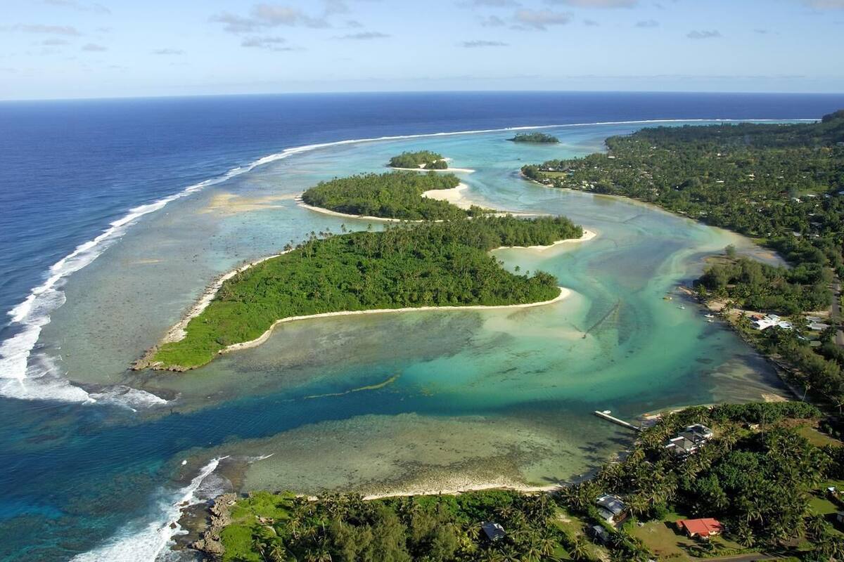 An aerial view of a coastal area with clear blue waters, sandy beaches, and lush greenery.