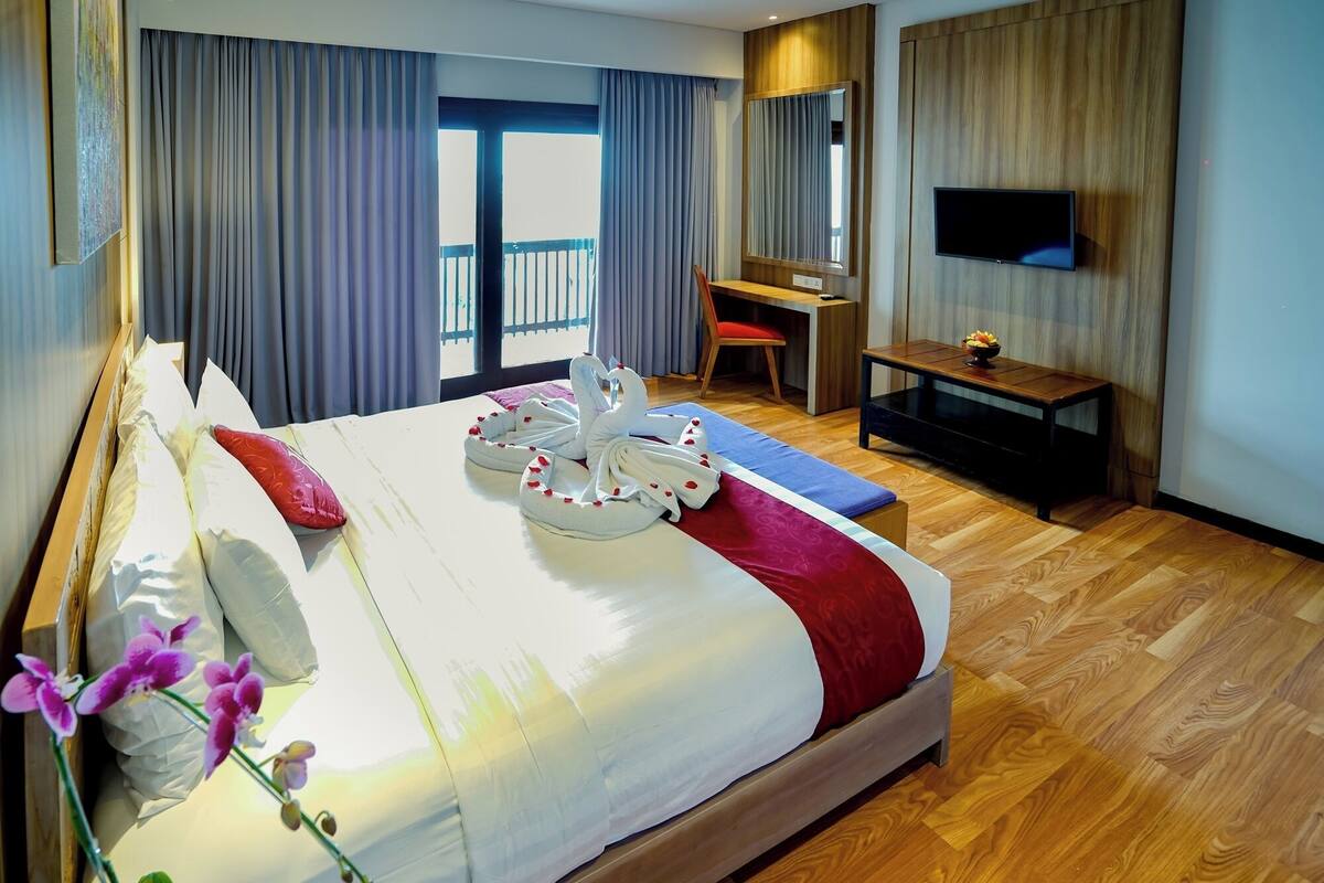 Une chambre d’hôtel avec un grand lit, un bureau, une télévision et un balcon avec vue.