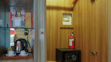 Una kitchenette compacta con refrigerador, cafetera y botellas de agua.