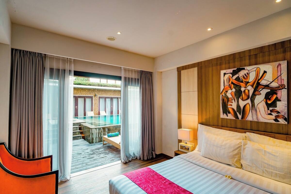 Une chambre d’hôtel avec un lit, un tableau au mur, une vue sur une piscine extérieure et un coin repas.