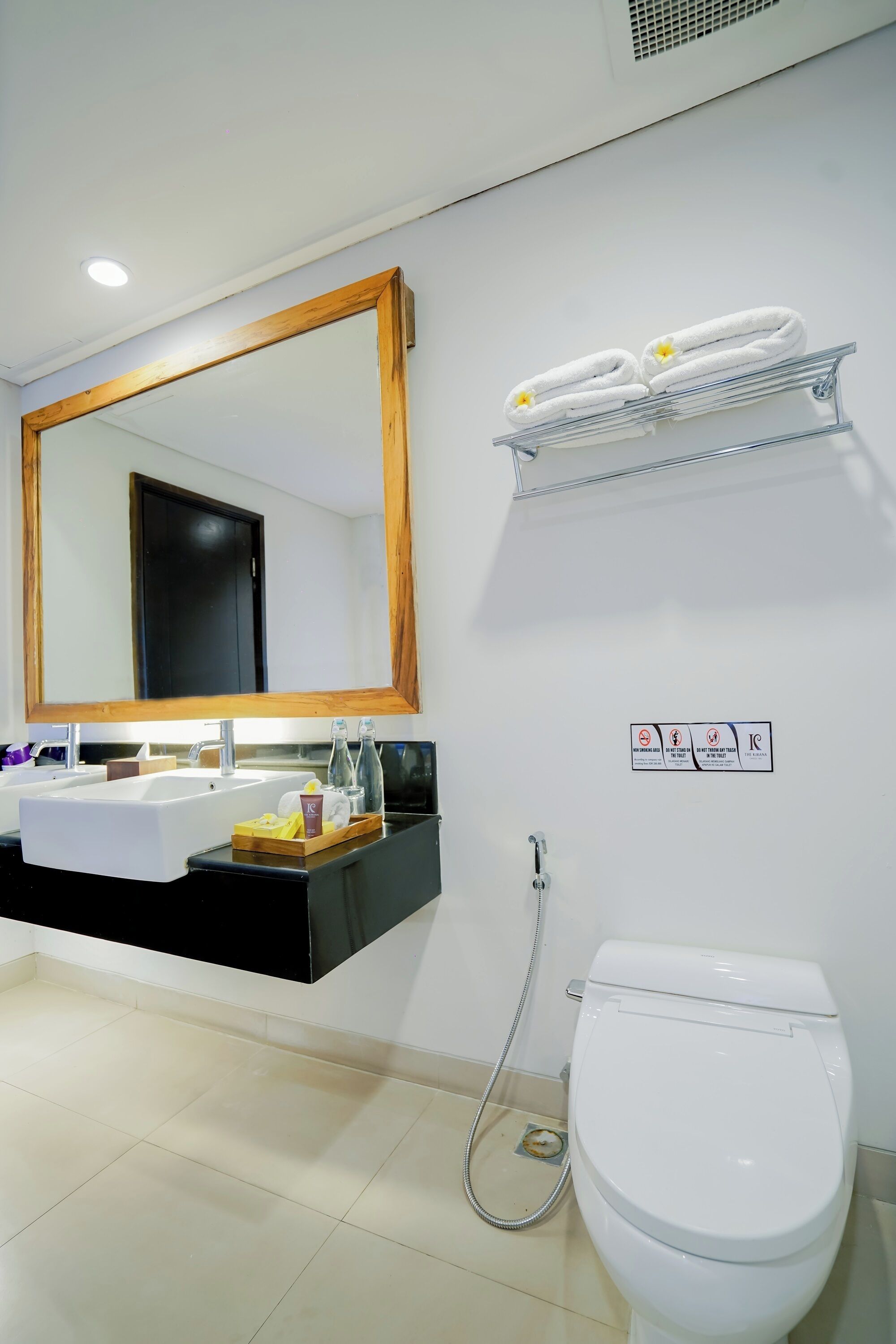 Un baño con un lavabo blanco, un espejo, un inodoro y un perchero para toallas.