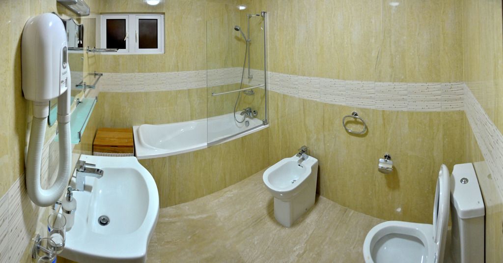 A bathroom with a sink, bidet, bathtub, and toilet.