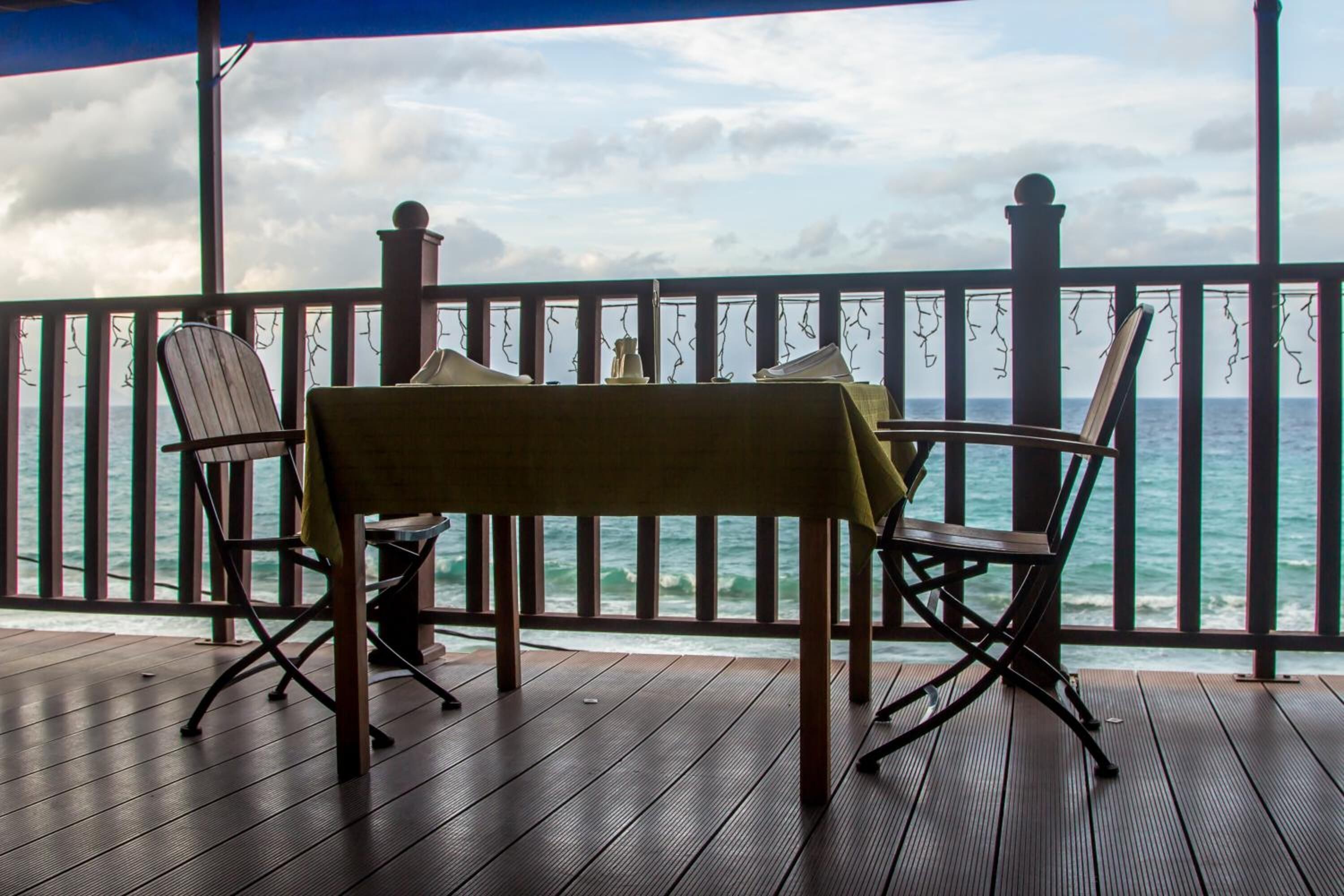 A wooden deck with a table and chairs overlooking the ocean.