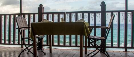 A wooden deck with a table and chairs overlooking the ocean.