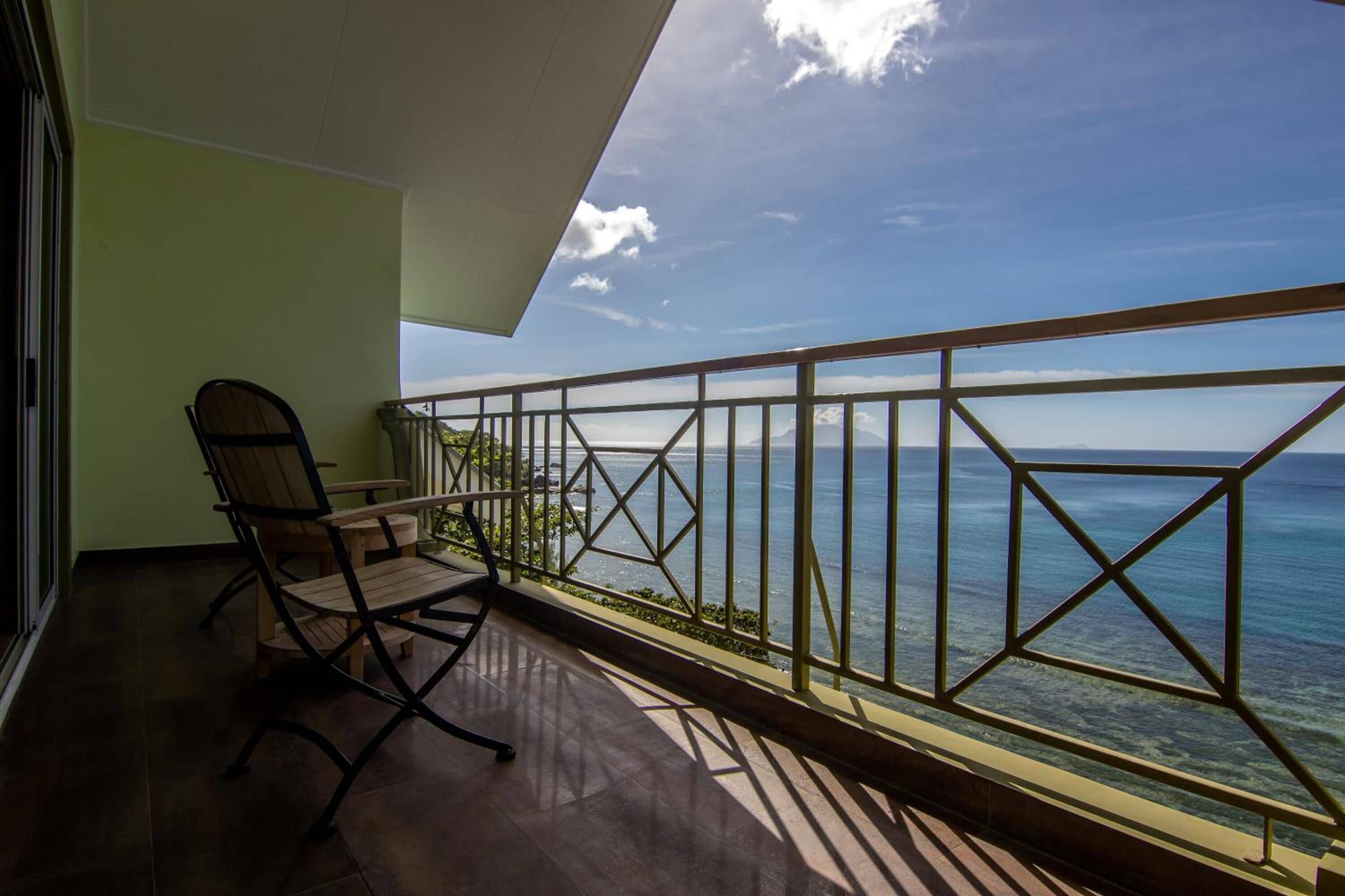 A balcony with a wooden floor, a chair, and a table.