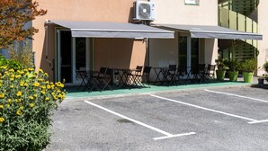 An outdoor seating area with tables and chairs, an air conditioning unit, and potted plants. - Hôtel Face West Le Pontet (Le Pontet)