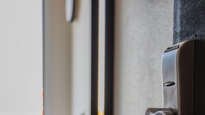 A door with a modern handle, a chair, and a wall-mounted mirror. - Hôtel Face West Le Pontet (Le Pontet)