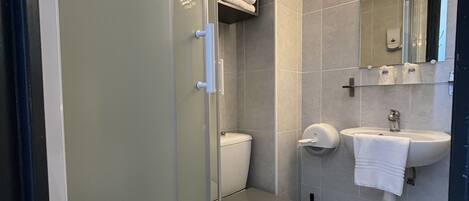 A modern bathroom with a glass shower enclosure, a toilet, a sink with a mirror, and a towel rack.