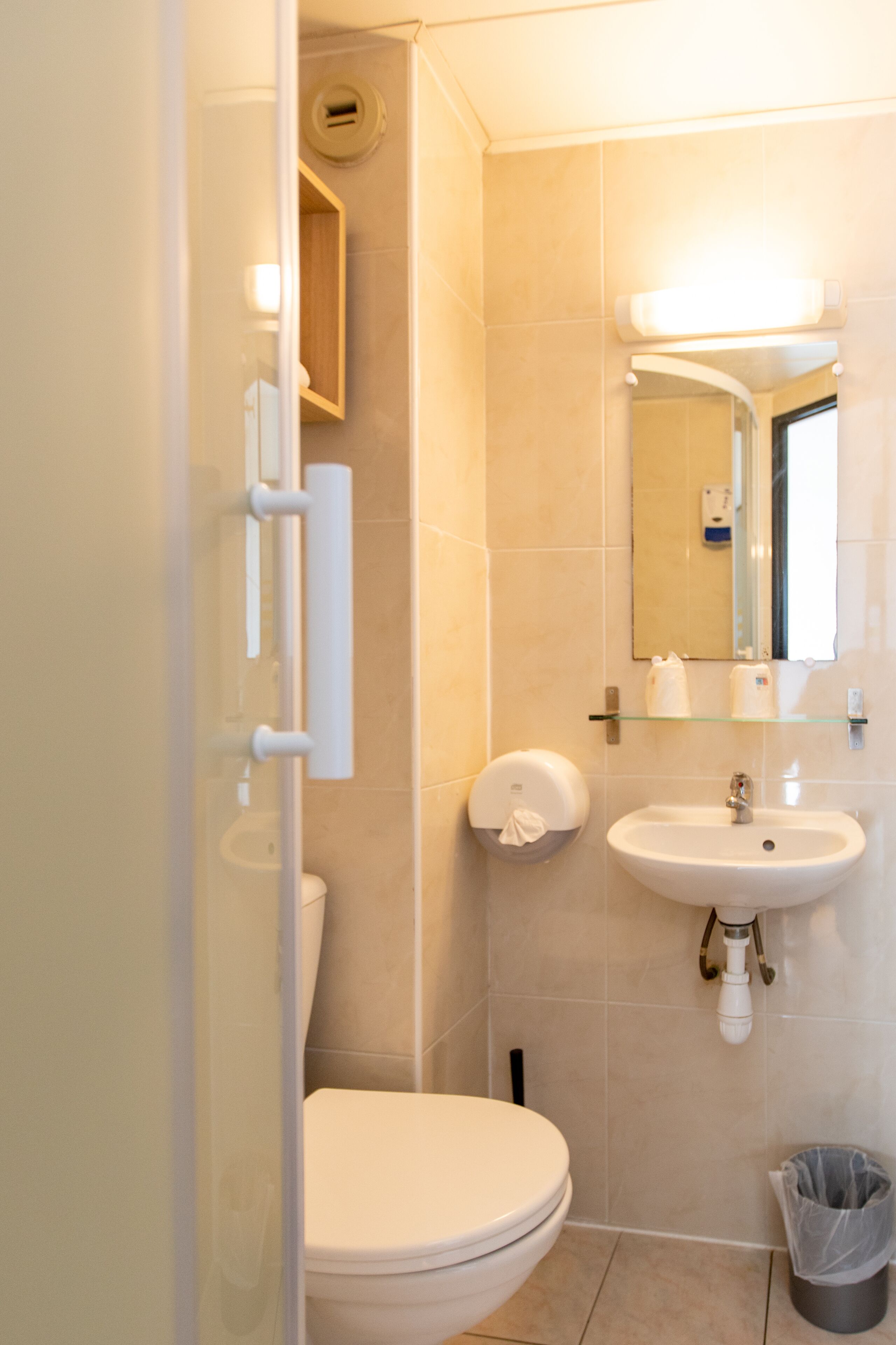 A bathroom with a toilet, sink, and mirror.