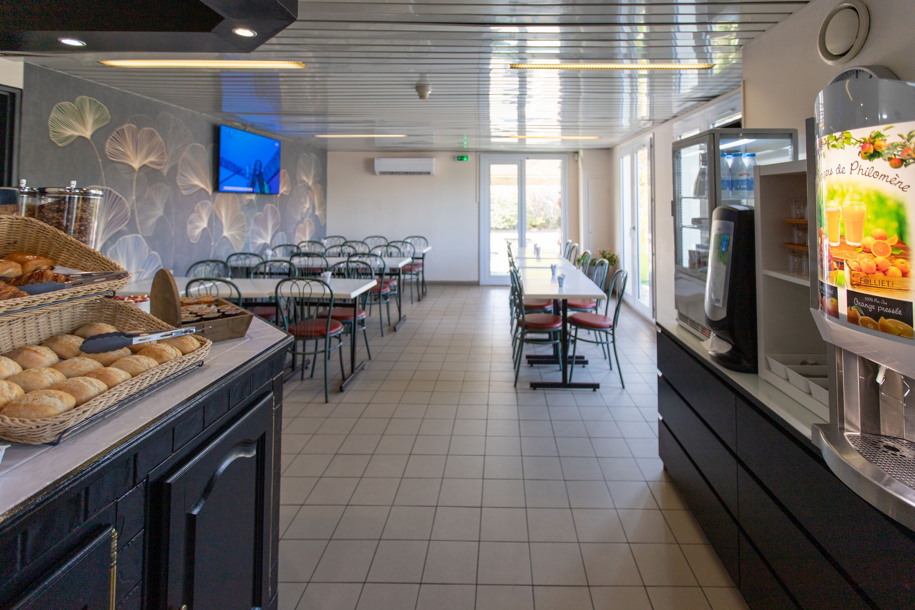 A modern dining area with a buffet setup, a television mounted on the wall, and a beverage dispenser.