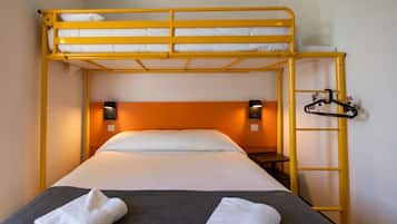 A bunk bed with a ladder, a bedside table, and two wall-mounted lamps.