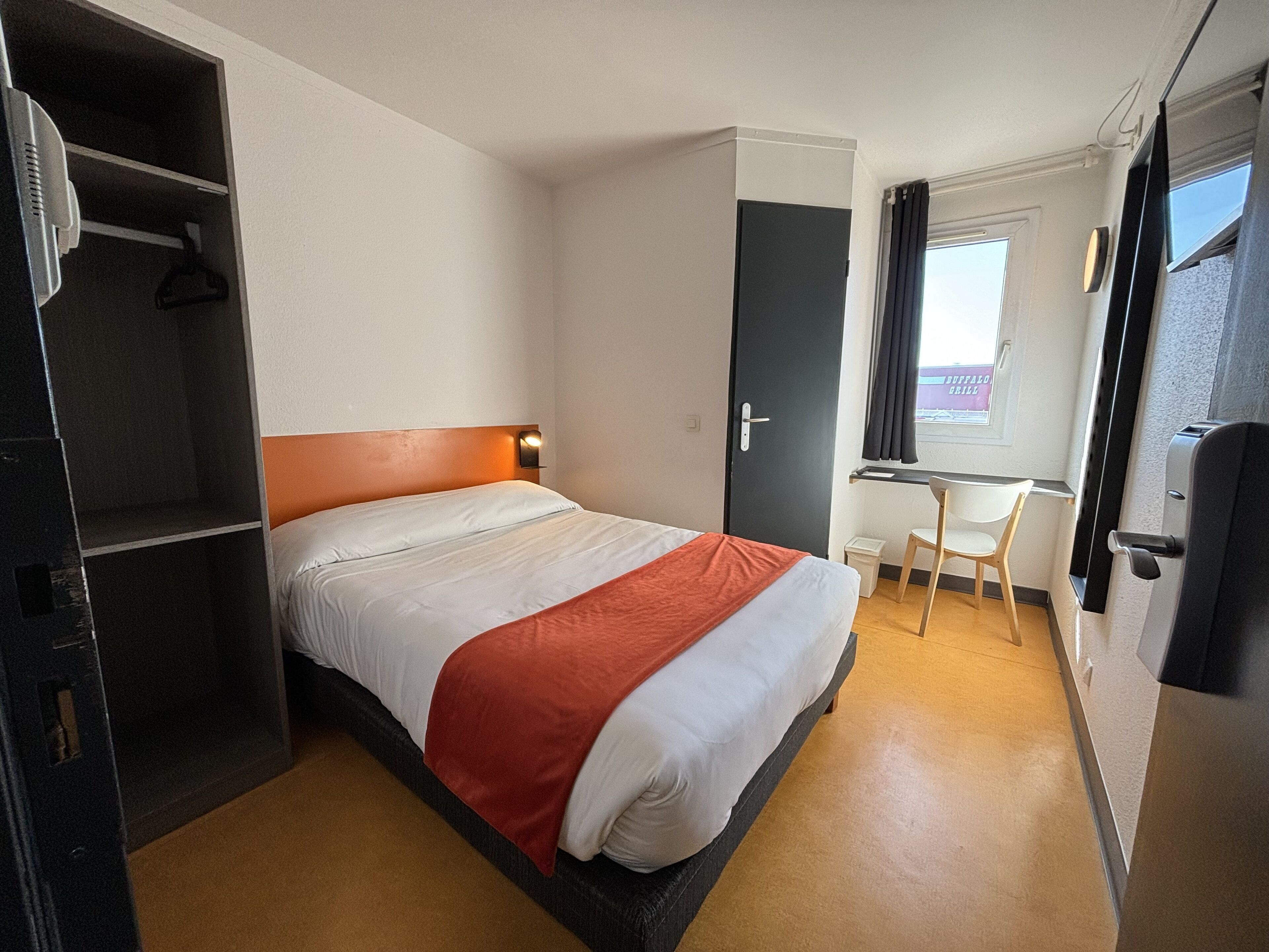 Une chambre d’hôtel comprenant un lit, un bureau, une chaise et une armoire.