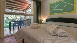 Una camera d'albergo con un letto, un tavolo con sedie, vista sull'esterno e un quadro appeso al muro.