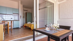 Camera d'albergo con zona pranzo, angolo cottura e un letto con asciugamani.