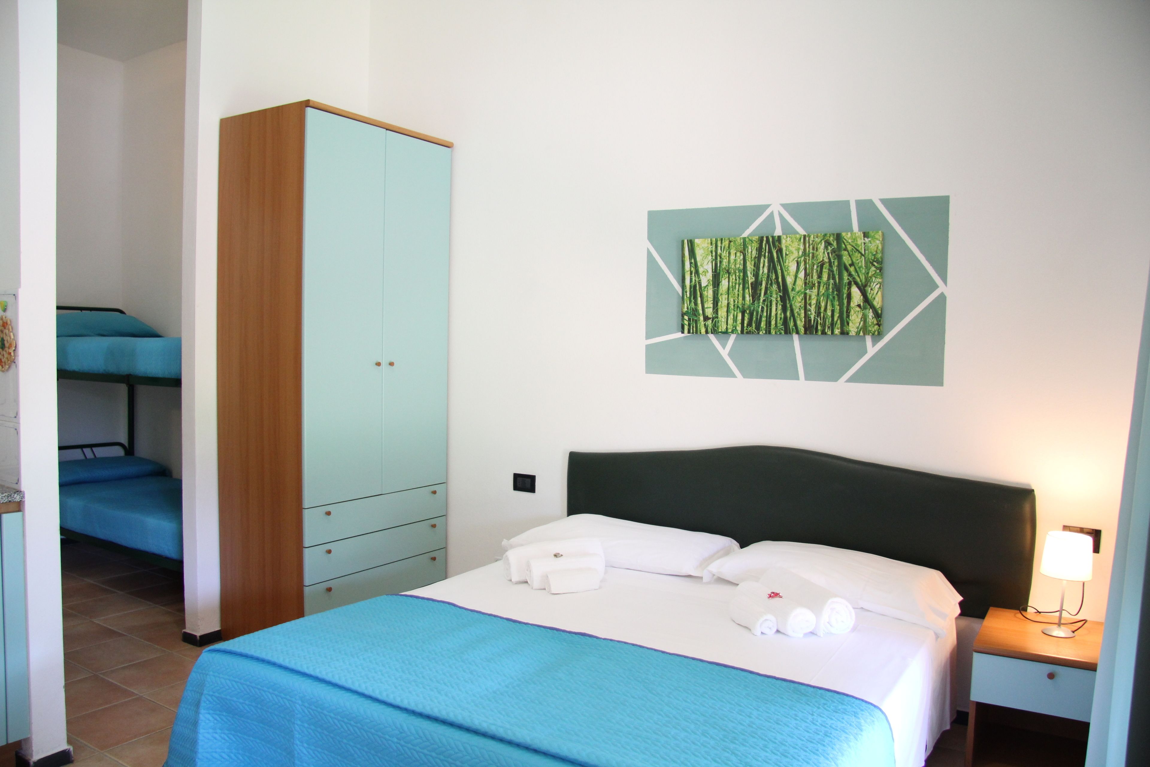 Une chambre d’hôtel comprenant un lit, une armoire, une table de chevet et une œuvre d’art accrochée au mur.