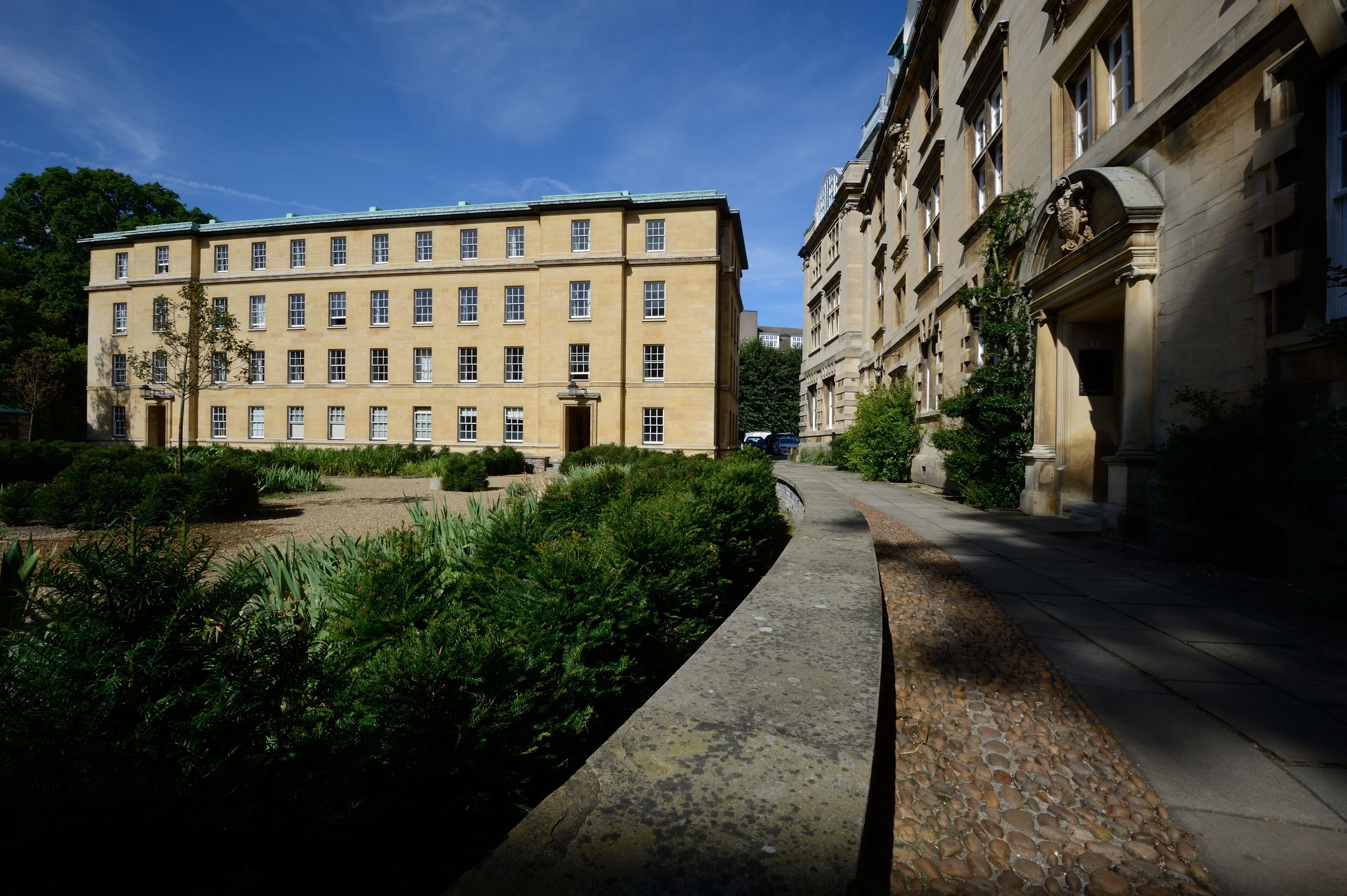 A courtyard with a building featuring a symmetrical facade, a central entrance, and a stone pathway.