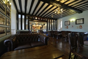 Step into a classic pub atmosphere with a long bench seating area, bar counter, and framed pictures on the walls.