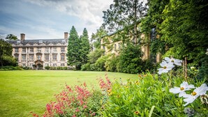 A large, historic building with a symmetrical facade, surrounded by lush greenery and a well-maintained lawn. - Christs College Cambridge (Cambridge)