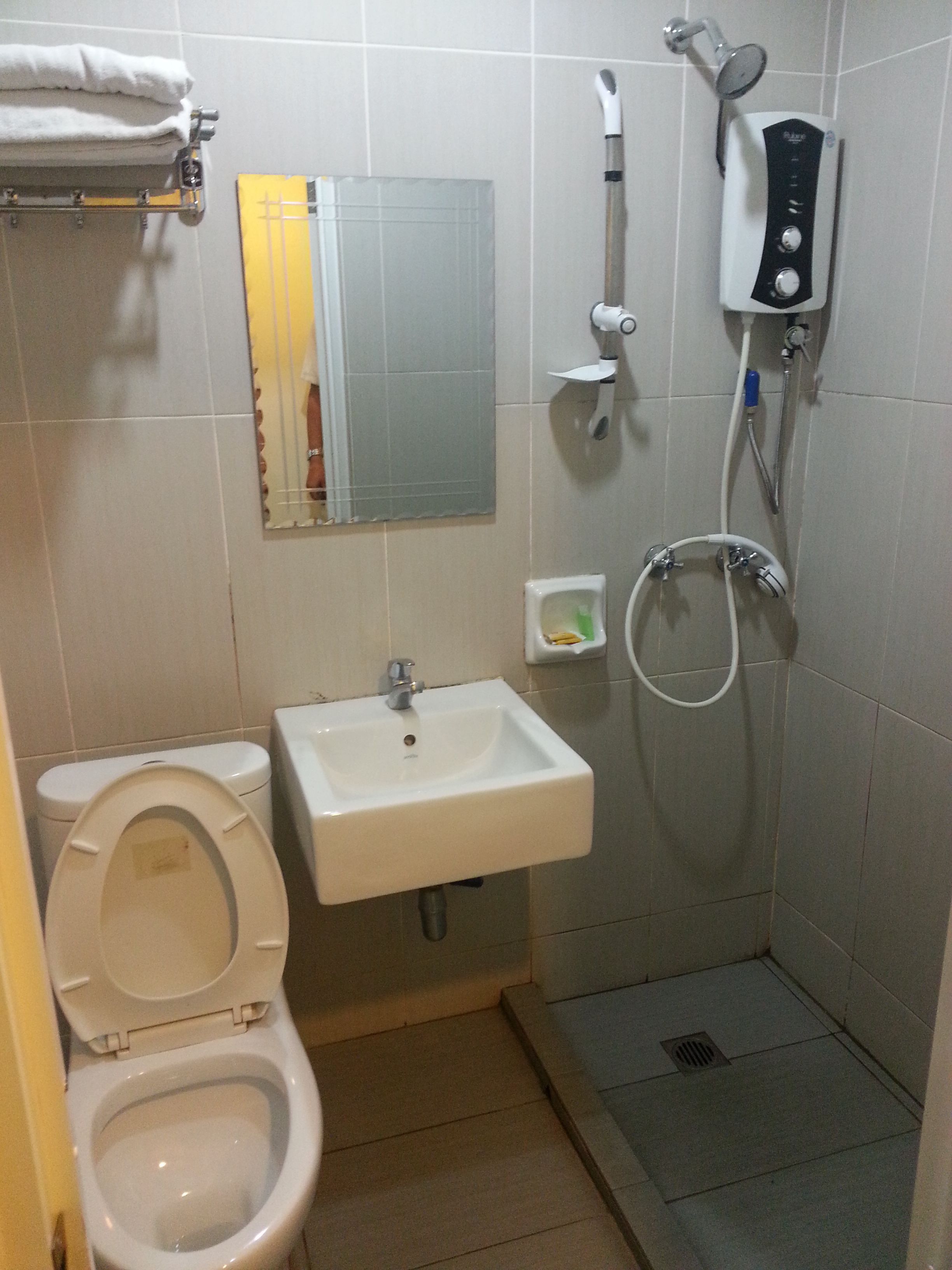 A small bathroom with a toilet, sink, and shower.