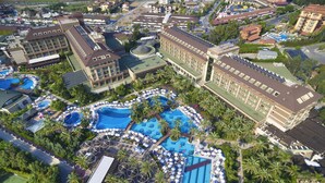 Vue aérienne d’un complexe hôtelier doté de plusieurs piscines, de palmiers et de bâtiments d’hôtel.