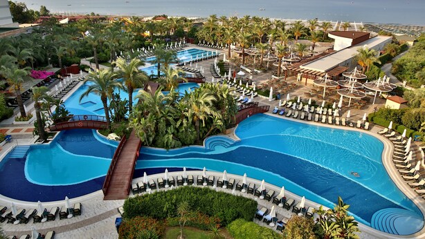 Un complexe hôtelier doté de plusieurs piscines, de palmiers et d’espaces de détente.