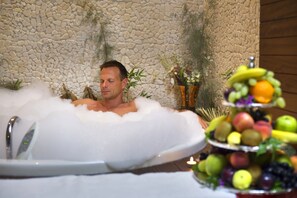 A man in a bathtub filled with bubbles, with a fruit arrangement on the side. - Sunis Evren Beach Resort Hotel & Spa  - All inclusive (Manavgat)